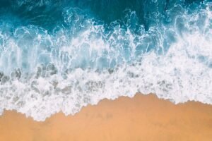 A breathtaking aerial shot capturing the waves crashing on a sandy beach from above.